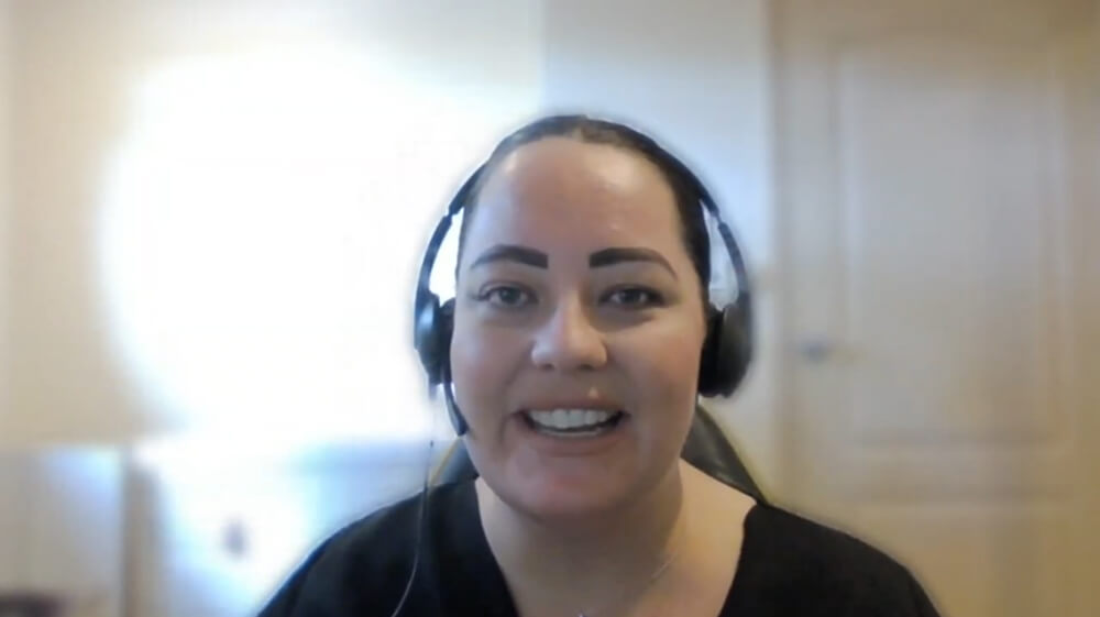 Person wearing a headset and smiling during a video call in a room with a closed door in the background.