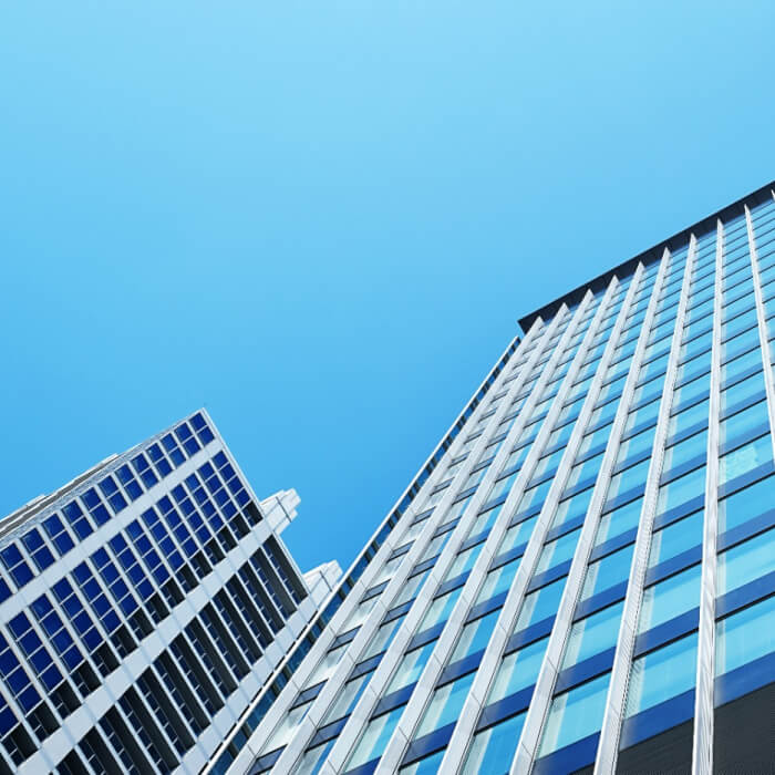 Low angle view of modern skyscrapers with glass facades against a clear blue sky.
