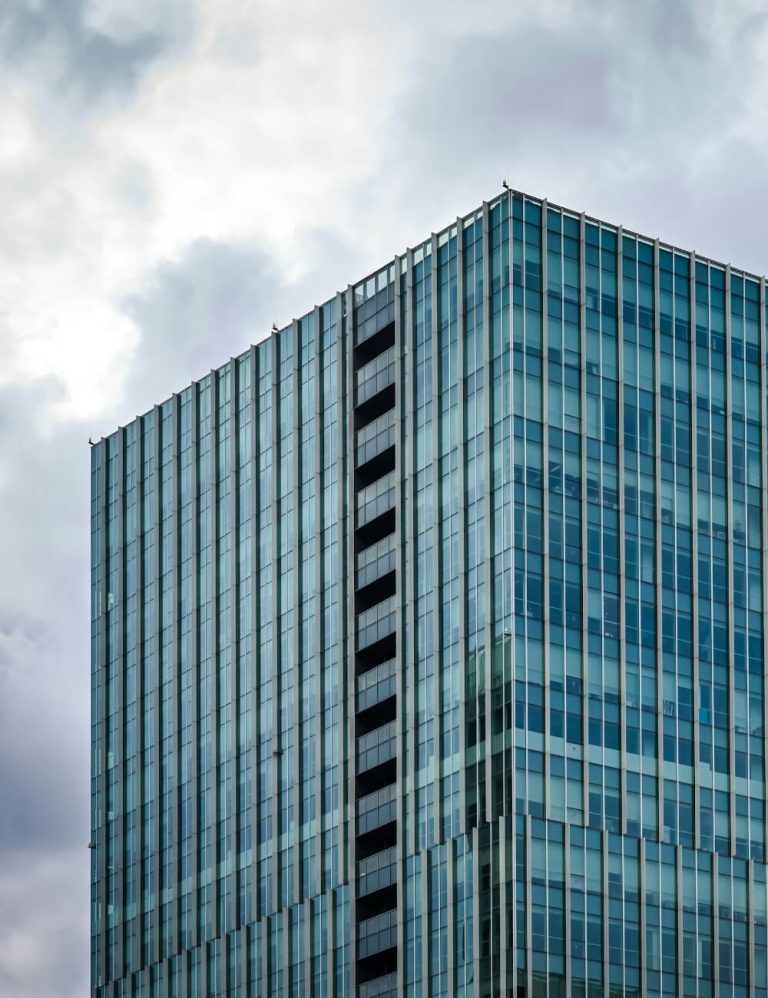 Glass-covered skyscraper corner against a cloudy sky.