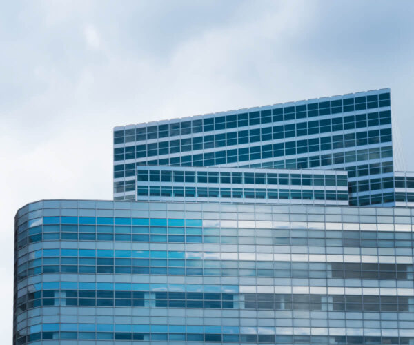 Modern glass building with a layered design against a cloudy sky.