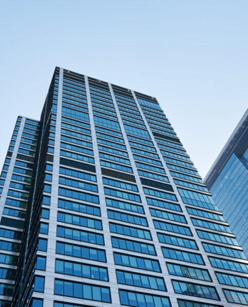 A tall modern office building with reflective glass windows against a clear blue sky.